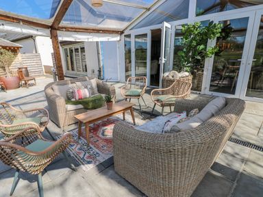 An outdoor seating area with a sofa, chairs, table, and a plant at Glamping Pod 1, Oldwalls, Llanrhidian, Gower