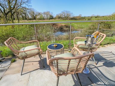 A seating area with chairs and a table overlooking a field at Glamping Pod 1 Oldwalls, Llanrhidian, Gower