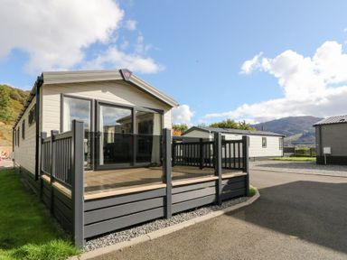 A mobile home with a deck and glass railing at Altair Lodge in 