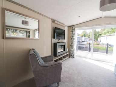A living room with a chair and television at Altair Lodge
