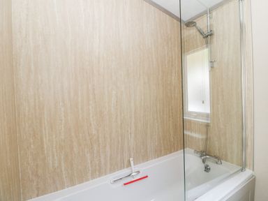 A bathtub with a showerhead and glass screen at Altair Lodge