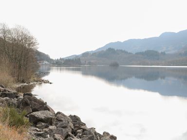 A lake surrounded by trees and mountains at Altair Lodge 