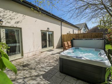 An outdoor area with a hot tub and sliding doors at Oak Tree Cottage, Oldwalls, Llanrhidian, Gower