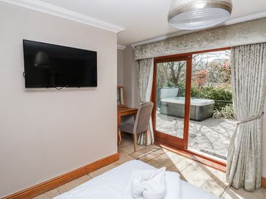 A bedroom with a television, desk, chair, and sliding door at Oak Tree Cottage in Oldwalls, Llanrhidian, Gower