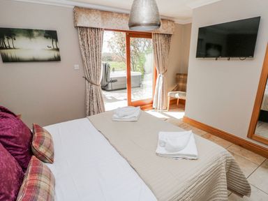 A bedroom with a bed and a television at Oak Tree Cottage in Oldwalls, Llanrhidian, Gower