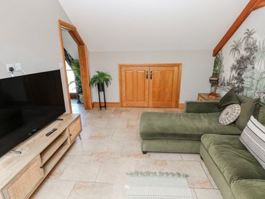 A living room with a television and sofa at Oak Tree Cottage in Oldwalls, Llanrhidian, Gower
