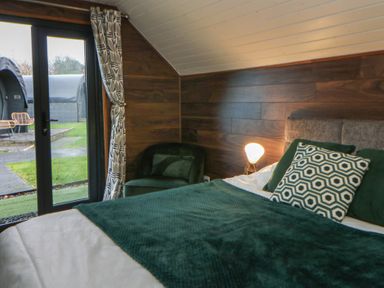 A bedroom with a bed and a chair at Garden lodge 3 Swansea