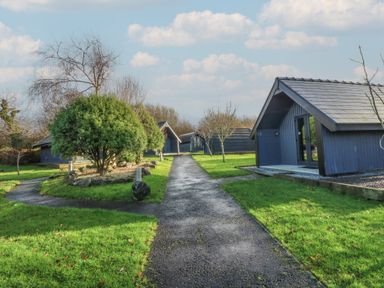 A pathway leading between cabins in a green area at Garden lodge 3 Swansea