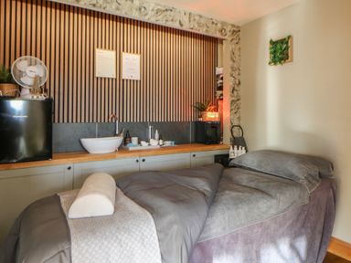 A treatment room with a massage table and sink at Garden lodge 3 Swansea