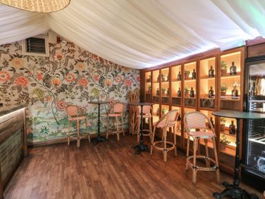A bar area with stools and a glass display cabinet at Garden lodge 3 in Swansea