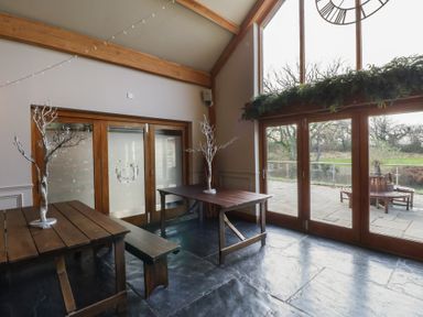 A dining room with tables and windows at Garden lodge 3 in Swansea