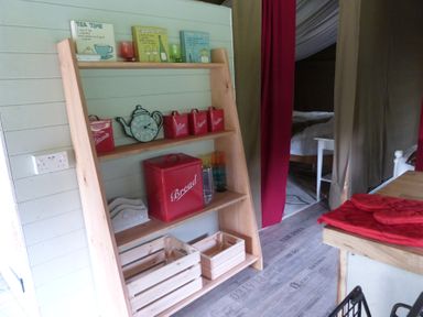 A shelf with containers and a clock in a kitchen at Ceri in Newcastle Emlyn