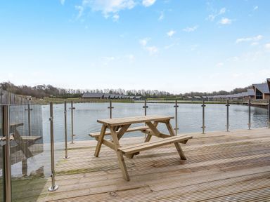An outdoor area with a picnic table and water view at Tranquillity 3 Warton near Carnforth