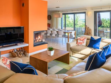 A living room with a fireplace and dining area at Nan's House Spa Marhamchurch