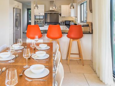 A kitchen with bar stools and a dining table at Nan's House Spa in Marhamchurch