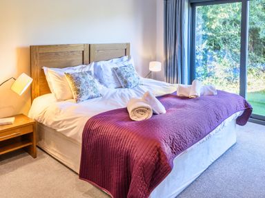 A bedroom with a bed and a sliding door at Nan's House Spa in Marhamchurch