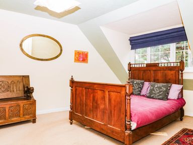 A bedroom with a wooden bed and bench at The Gables in Teignmouth