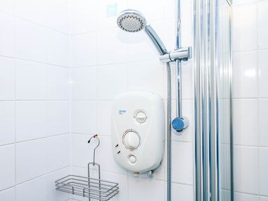 A shower setup with water heater and showerhead at The Gables in Teignmouth