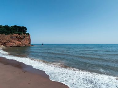 A beach with cliffs and ocean waves at 4 The Gables in Teignmouth