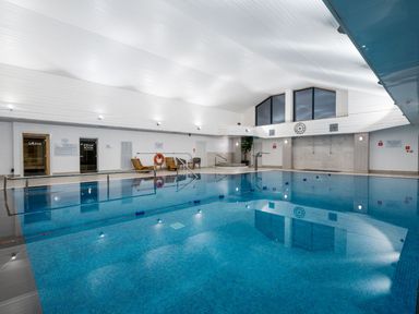 An indoor pool with lounge chairs and sauna entry at The Weir in North Berwick