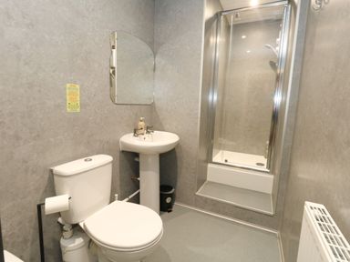 A bathroom with a toilet, washbasin, and shower at The Old Barn in Stourton Caundle near Stalbridge