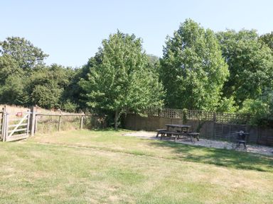 A garden with a picnic table and trees at The Old Barn in Stourton Caundle near Stalbridge