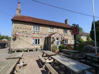 A pub with outdoor seating and bunting at The Old Barn in Stourton Caundle near Stalbridge
