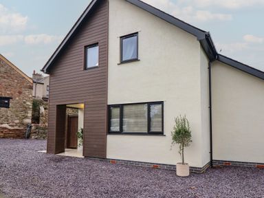 An exterior view of a house with gravel and a plant at Pistyll Ddu in Brynsiencyn near Llanfairpwllgwyngyll