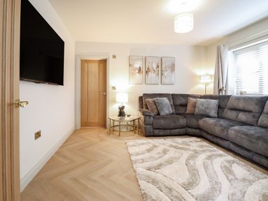 A living room with a large sofa and a television at Pistyll Ddu near Brynsiencyn