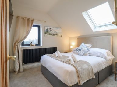 A bedroom with a bed, decorative pillows, and a window at Pistyll Ddu in Brynsiencyn near Llanfairpwllgwyngyll