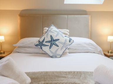 A bed with pillows and a decorative cushion at Pistyll Ddu in Brynsiencyn near Llanfairpwllgwyngyll