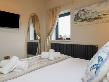 A bedroom with a bed, towels, and a television at Pistyll Ddu in Brynsiencyn near Llanfairpwllgwyngyll