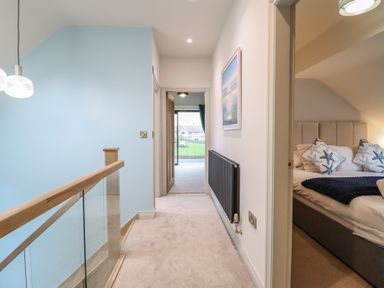 A hallway with a staircase and bedroom door at Pistyll Ddu in Brynsiencyn near Llanfairpwllgwyngyll
