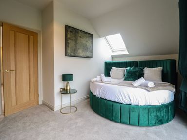 A bedroom with a round bed and a lamp at Pistyll Ddu in Brynsiencyn near Llanfairpwllgwyngyll