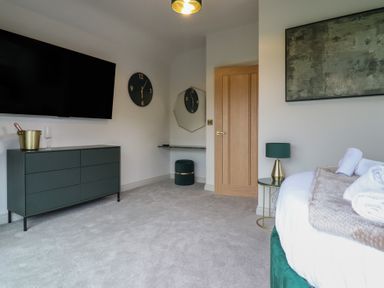 A bedroom with a television and clock above a dresser at Pistyll Ddu in Brynsiencyn near Llanfairpwllgwyngyll