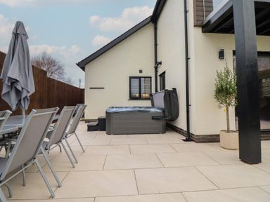 An outdoor area with a hot tub and dining set at Pistyll Ddu Brynsiencyn near Llanfairpwllgwyngyll