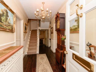 A hallway with a staircase and chandelier at Ladye Park in Liskeard