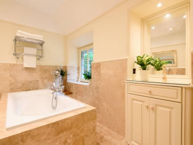 A bathroom with a bathtub, sink, towels, and plants at Ladye Park in Liskeard