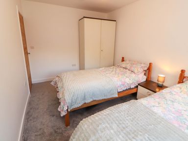 A bedroom with two beds and a wardrobe at Westerlodge in Threlkeld near Keswick
