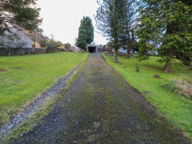 A gravel driveway leading to a building surrounded by grass and trees at Westerlodge Threlkeld near Keswick