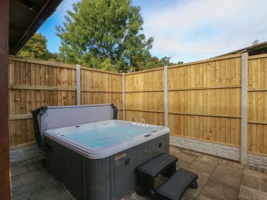 A hot tub with steps and wooden fence at Woodlands View in Leek
