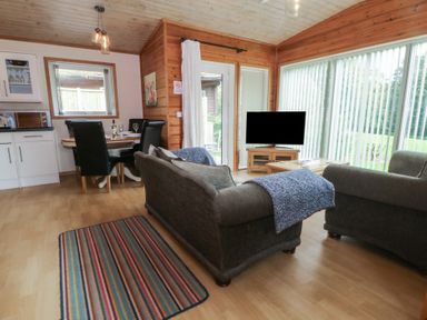 A living room with a sofa and dining table at Woodlands View in Leek