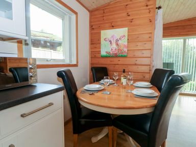 A dining room with a round table and chairs at Woodlands View in Leek