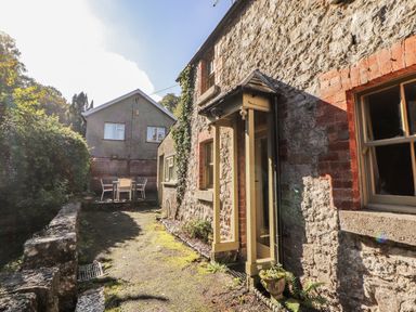 A view of a stone wall with a door and table at Rock Cottage in Milnthorpe