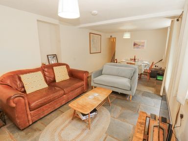 A living room with a sofa, coffee table, and dining area at Rock Cottage in Milnthorpe