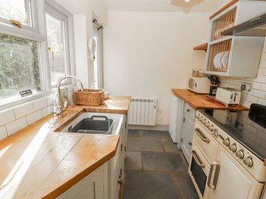 A kitchen with a sink, countertop, and appliances at Rock Cottage in Milnthorpe
