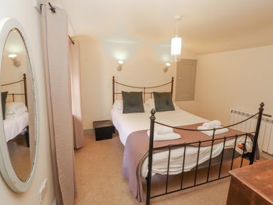 A bedroom with a bed and mirror at Rock Cottage in Milnthorpe