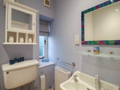 A bathroom with a toilet, sink, and shelf at Nutshell in Aldeburgh