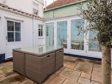 A garden with a glass table and plants at The Nutshell in Aldeburgh