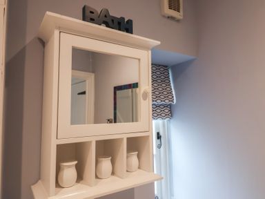 A cabinet with a mirror and vases in a bathroom at The Nutshell in Aldeburgh